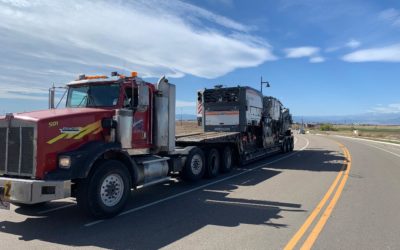 Midstate Companies heavy haul trucking service carrying large road maintenance equipment.
