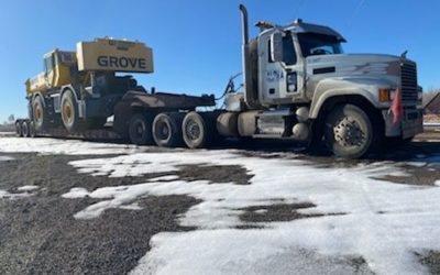 Alpha Milling heavy haul trucking service carrying large road maintenance equipment.